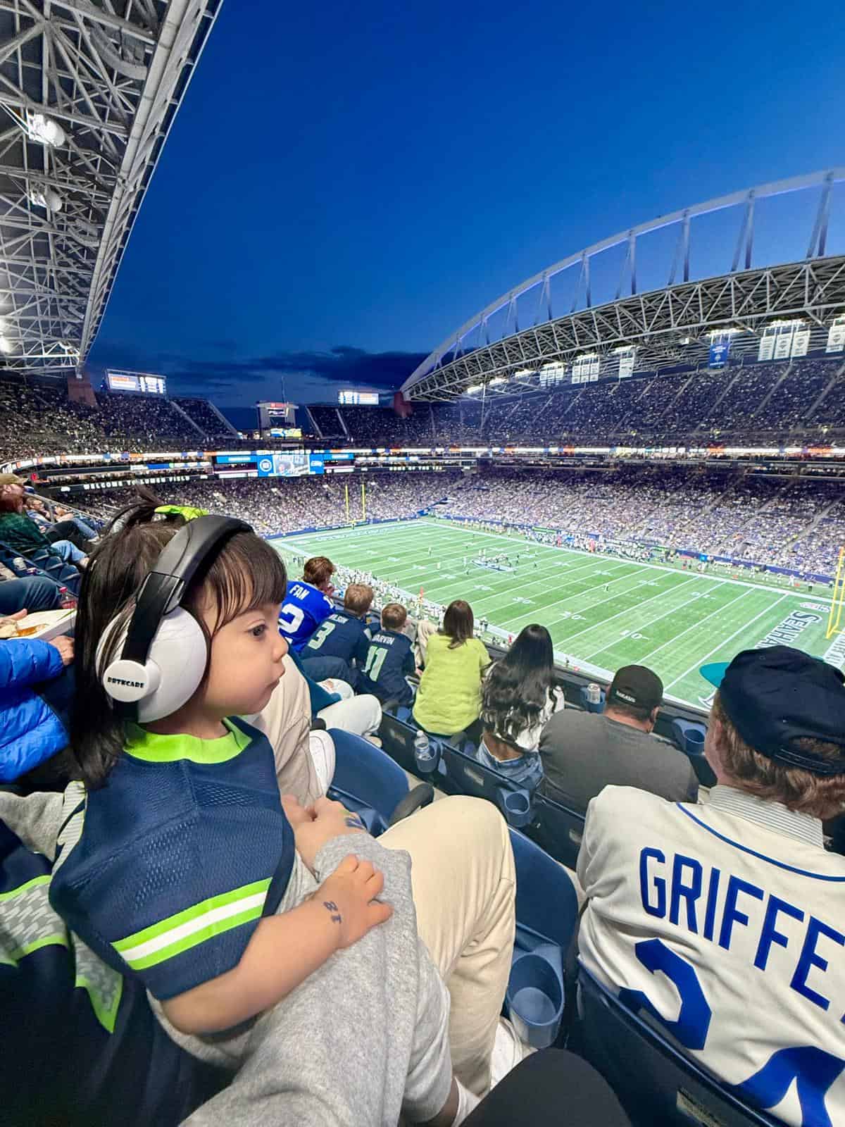 Ellie Guay wearing a headset in the crowd at a Seattle Seahawks football game